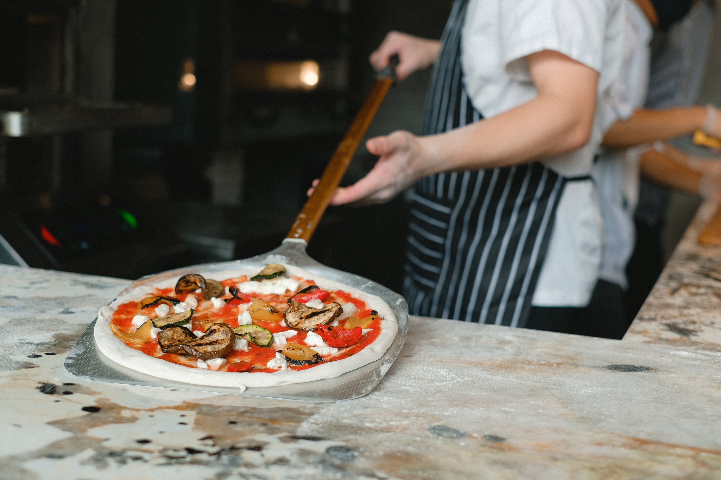 Man Holding a Pizza on a Pizza Shovel 